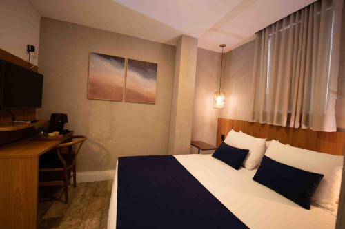 a hotel room with a bed and a desk and a television at Leblon Design Hotel in Rio de Janeiro