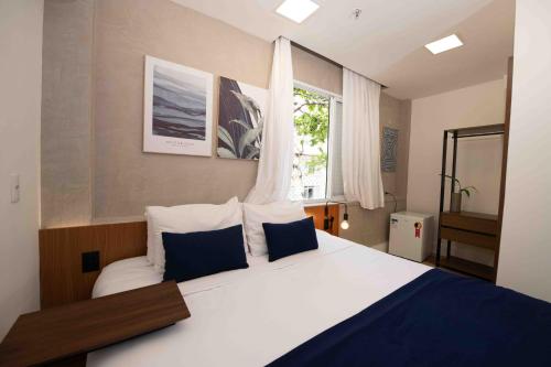 a bedroom with a large bed with blue and white pillows at Leblon Design Hotel in Rio de Janeiro