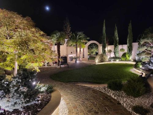 a garden at night with a lawn and trees at Sika Grand Palladium Garden & Spa Central Apartment Arad in Arad