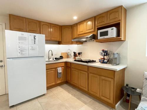 uma cozinha com armários de madeira e um frigorífico branco em 9AM Check-in Coastal Getaway - Luxe Suite near Cliff, Lake & Local Shops em Daly City