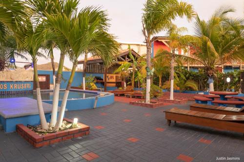 a courtyard with palm trees and benches in a resort at Nos Krusero Apartments in Sabana Westpunt