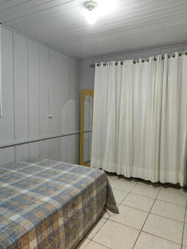 um quarto com uma cama e cortinas brancas em Casa para 6 pessoas Oktoberfest em Blumenau