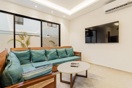 Una sala de estar con un sofá azul y una mesa. en Cenote Korima - Relax in Paradise - Stunning House with Pool, en Cancún