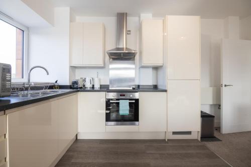 a kitchen with white cabinets and a sink and a stove at Entire 1 Bed - No. 45 - Free Parking - The Cosy Collection Ltd in York