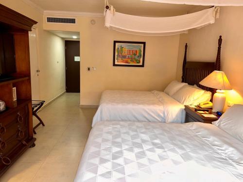 a hotel room with two beds and a table with a lamp at Holiday Inn Merida by IHG in Mérida