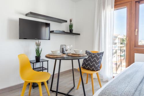 a dining room with a table and yellow chairs at Estudio Frankie in L'Escala