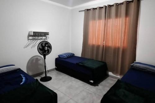 a room with two beds and a fan and a window at North Park 388 in Campo Grande