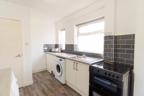 a kitchen with a sink and a washing machine at 2 Bedroom House By Maison Stays - Free Parking in Nottingham