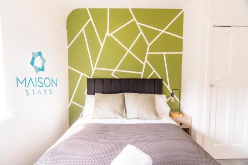 a bedroom with a bed and a green wall at 2 Bedroom House By Maison Stays - Free Parking in Nottingham