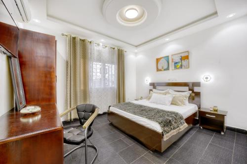 a hotel room with a bed and a desk and a chair at Cosy Home in Douala