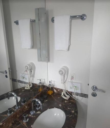 a bathroom with a sink and two hair dryers at Flat Hotel São Paulo, no coração de Moema in São Paulo
