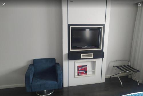 um quarto com uma televisão e uma cadeira azul em Flat Hotel São Paulo, no coração de Moema em São Paulo