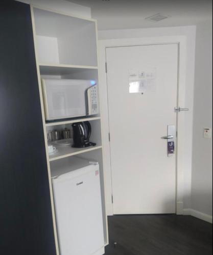 a kitchen with a white refrigerator and a microwave at Flat Hotel São Paulo, no coração de Moema in São Paulo