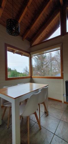 a dining room with a table and two windows at Cabaña Victoria I in San Martín de los Andes