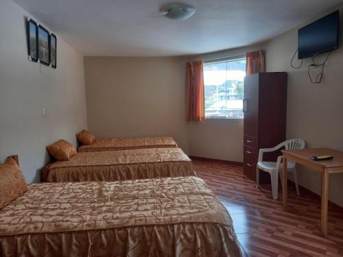 een hotelkamer met 2 bedden, een bureau en een raam bij hotel bello horizonte de cotahuasi in Cotahuasi