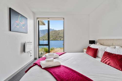 a bedroom with a large white bed with a window at Residence du Lac by Staysouth in Queenstown