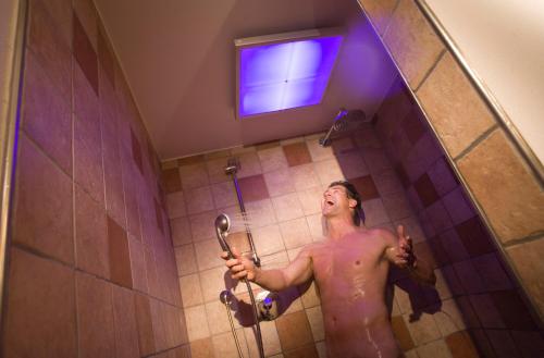 mężczyzna stojący pod prysznicem w łazience w obiekcie Hotel Sonne w mieście Tux