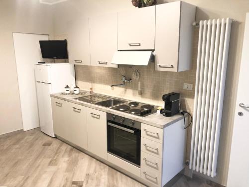 een keuken met witte kasten en een fornuis met oven bij Colomba Apartment in Tolè
