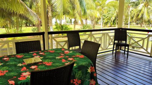 una mesa y sillas en un porche con mesa y mesa en HUAHINE - Hibiscus House, en Haapu