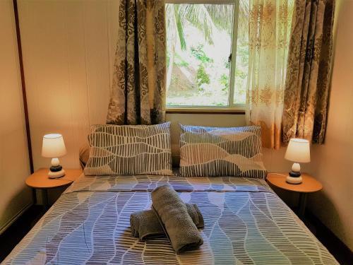1 dormitorio con cama con almohadas y ventana en HUAHINE - Hibiscus House, en Haapu