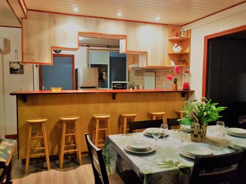 a dining room with a table and a kitchen at HUAHINE - Hibiscus House in Haapu