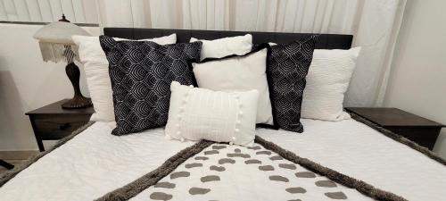 ein Bett mit schwarzen und weißen Kissen darauf in der Unterkunft Villa Las Palmeras South Miami in Miami