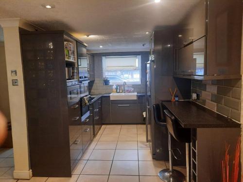 a kitchen with black cabinets and a tile floor at Home Away in a Close in Thamesmead