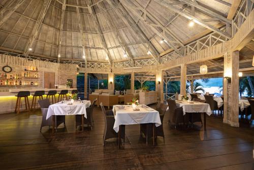 restauracja z białymi stołami i krzesłami oraz sufitem w obiekcie Lembeh Resort w mieście Bitung