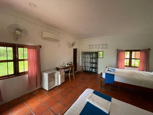 a bedroom with two beds and a desk in it at Kep Lodge in Kep