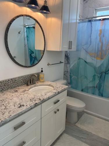 a bathroom with a sink and a toilet and a mirror at Beach Glass - Island Getaway in Corpus Christi