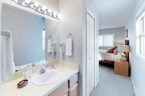 a bathroom with a sink and a mirror and a bed at Big Horn by DC in Big Sky