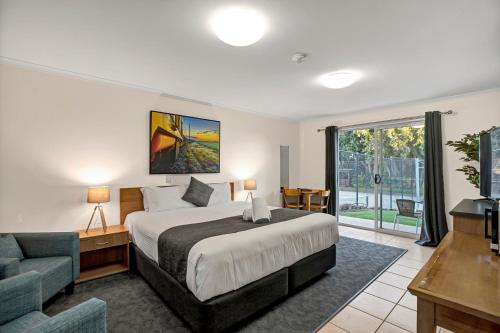 a bedroom with a bed and a couch and a chair at Windmill Motel & Events Centre in Mackay