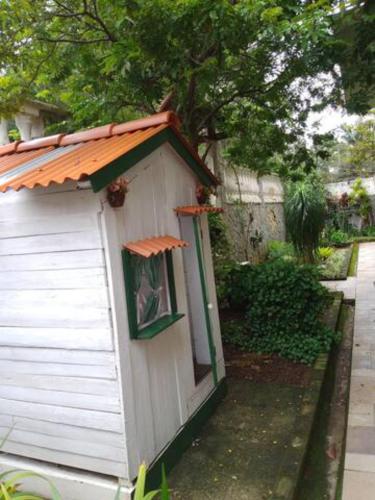 a small white shed with an orange roof at Cantinho da Vovó Regina in Miguel Pereira