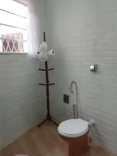a bathroom with a toilet with a wooden pole at Cantinho da Vovó Regina in Miguel Pereira
