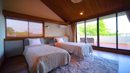 een slaapkamer met 2 bedden en een groot raam bij Alivio ATAMI in Atami