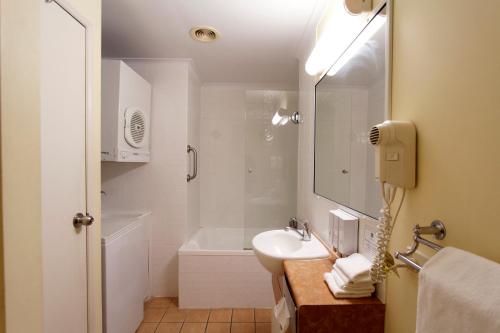 uma casa de banho com um lavatório e uma banheira em Windmill Motel & Events Centre em Mackay