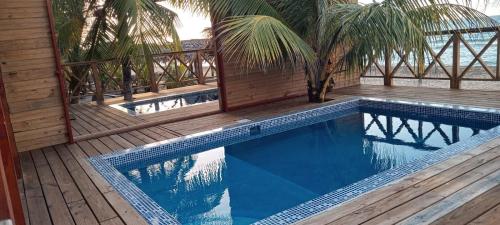 a swimming pool with a wooden deck next to a house at Villa Devonia - Beachfront Cabins with Pool at Tela, HN in Tela