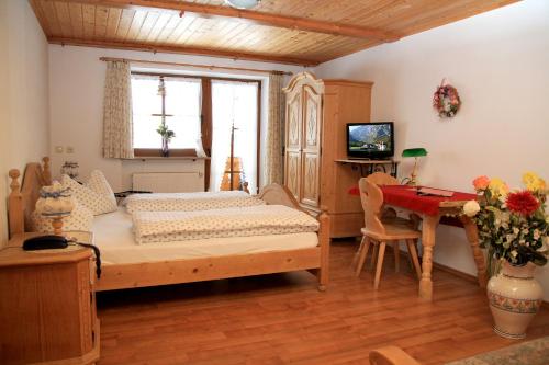 Schlafzimmer mit einem Bett, einem Schreibtisch und einem TV in der Unterkunft Gästehaus Obersulzberglehen in Schönau am Königssee