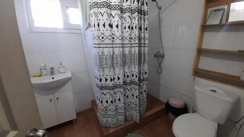a bathroom with a toilet and a sink and a shower curtain at Casa Loncoche Villarrica con 3 Dormitorios in Loncoche