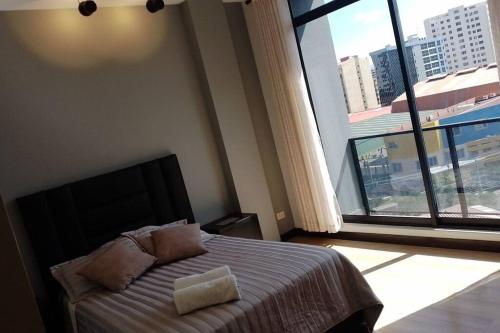 コチャバンバにあるDepartamento acogedor y modernoのベッドルーム1室(ベッド1台、大きな窓付)