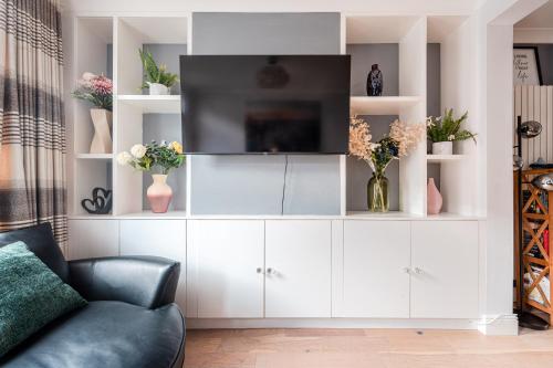 a living room with a tv on a white entertainment center at SuffStay in Ipswich