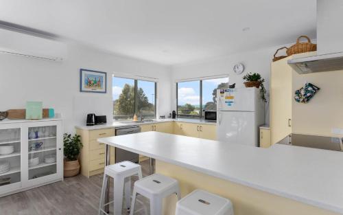 a kitchen with a white counter and stools in it at Great Family Holiday House in Central Location in Victor Harbor