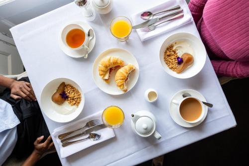 - une table avec des assiettes de produits pour le petit-déjeuner et des tasses de café dans l'établissement Quamby Estate, à Hagley