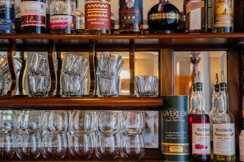 a shelf filled with glasses and bottles of alcohol at Quamby Estate in Hagley