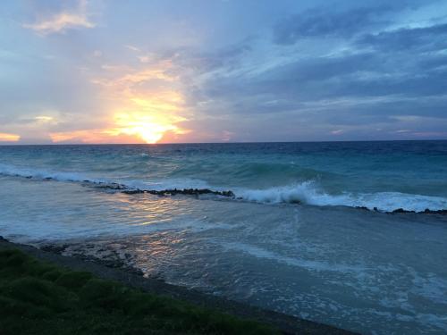 a sunset over the ocean with a wave at Red Ground Village in San Andrés