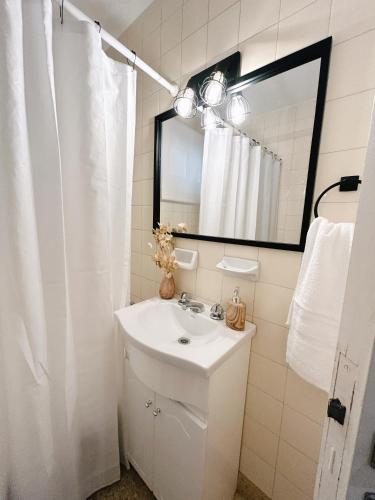 een witte badkamer met een wastafel en een spiegel bij Alquiler temporario in Bahía Blanca