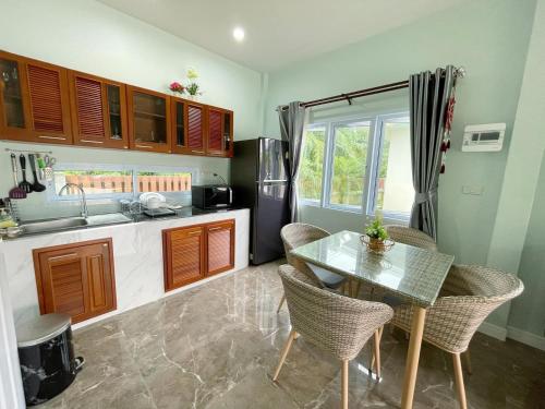 uma cozinha com uma mesa e cadeiras e um frigorífico em อิงแลนด์เฮ้าส์แอนด์พูล England8House&Pool em Khanom