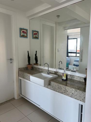 uma casa de banho com um lavatório e um espelho grande em Maravilhosa cobertura duplex vista mar em Salvador