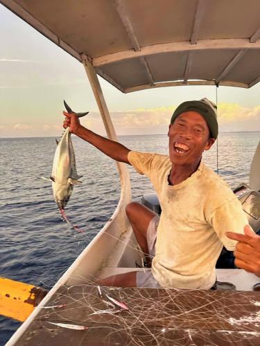 a man holding up a fish in a boat at Island Garden Huts Lembongan in Nusa Lembongan