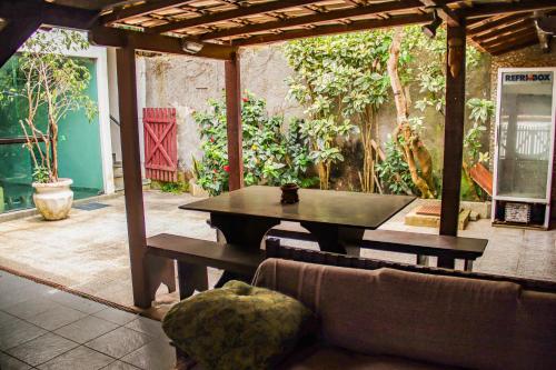 un patio con mesa y sofá en Recanto da Árvore Suítes, en Arraial do Cabo